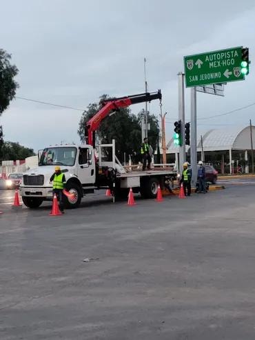 Camión blanco con pluma articulada en calle con conos