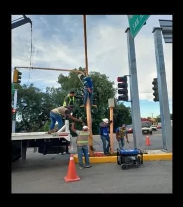 Trabajadores instalando semáforo en intersección